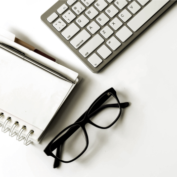 notebook, keyboard, and eyeglasses on a table