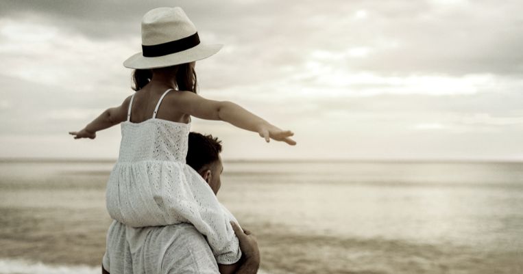 a child sitting on top of her father's shoulders